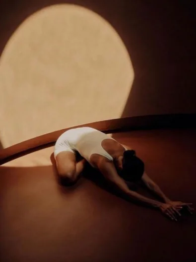 A student resting in child's pose in amber light